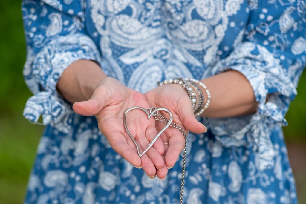 Photo of Darlene Coleman's open hands, holding a silver heart necklace