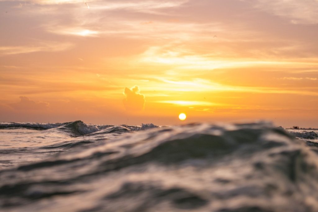 Photo of sun setting behind ocean waves