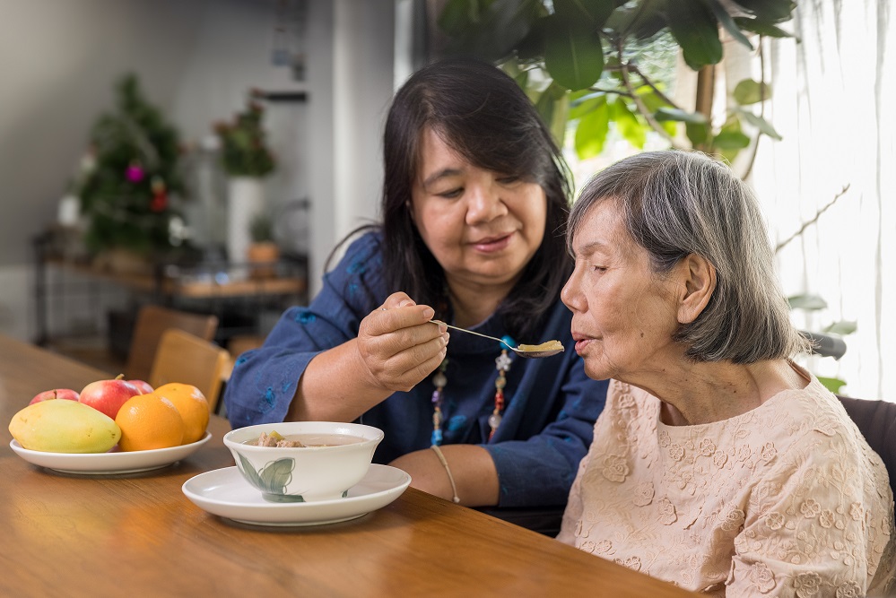 Photo of caregiver feeding elderly woman